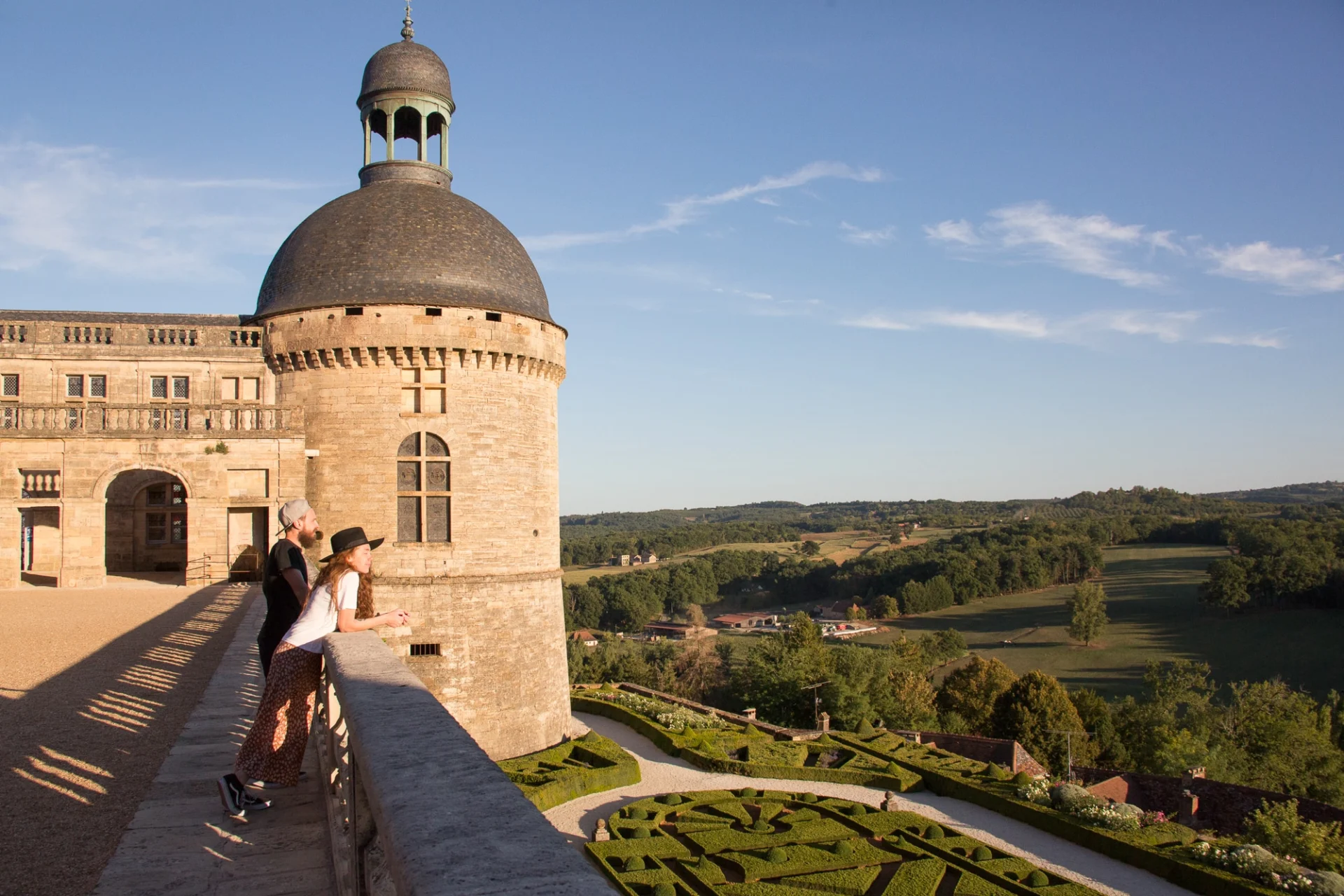 Façade du château de hautefort avec deux personnes regardant au loin les jardins du château